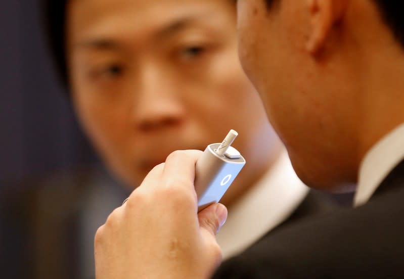 FILE PHOTO: Attendees try British American Tobacco's new tobacco heating system device 'glo' after a news conference in Tokyo