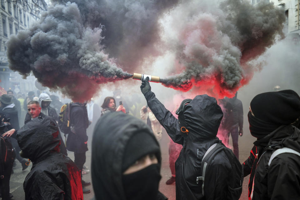 A protester holds up a flare during a demonstration in Lyon, central France, Tuesday, Dec. 17, 2019. Workers at the Eiffel Tower, teachers, doctors, lawyers and people from across the French workforce walked off the job Tuesday to resist a higher retirement age, or to preserve a welfare system they fear their business-friendly president wants to dismantle. (AP Photo/Laurent Cipriani)