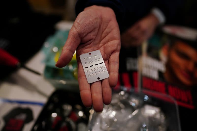 A vendor holds up a military-style dog tag calling for the return of Israeli hostages who have been held in the Gaza Strip since they were seized by Hamas gunmen on October 7, in Tel Aviv