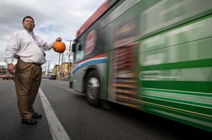 Anthony Oxendine, owner of Spring Valley Funeral Homes hands out pumpkins to passing motorists on West Broadway, in Louisville. Oct. 7, 2021