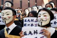FILE PHOTO: University students wearing Guy Fawkes masks pose during a news conference to support anti-government protests before their graduation ceremony at the Hong Kong Polytechnic University in Hong Kong