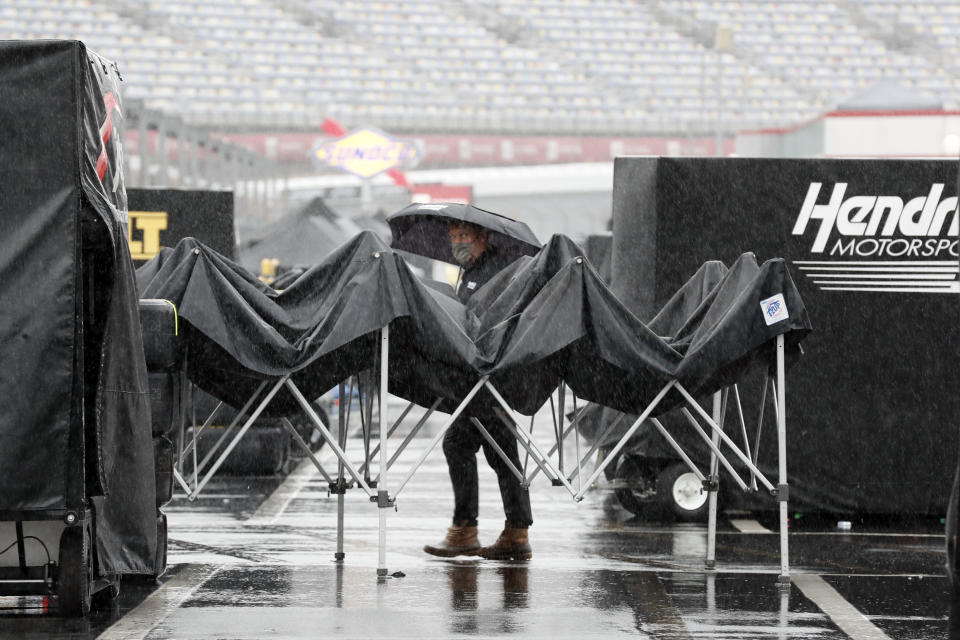 A man walks through the infield as rain falls before a NASCAR Cup Series auto race at Charlotte Motor Speedway Wednesday, May 27, 2020, in Concord, N.C. (AP Photo/Gerry Broome)