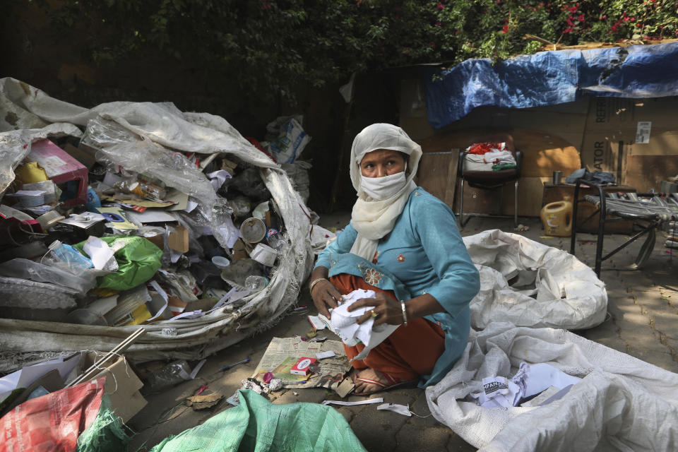 Manuwara Begun, 46, sorts out garbage collected from households in New Delhi, India, Tuesday, March 9, 2021. Begun lives in a cardboard hut behind a five-star hotel in the heart of New Delhi and feels the inequity keenly. Trash pickers often find it hard to get vaccines because they are not considered by the government to be essential workers or cannot afford to wait at overburdened public hospitals for free shots. Chintan estimates that each year, those like her save the local government over $50 million and eliminate over 900,000 tons of carbon dioxide by diverting waste away from landfills. (AP Photo/Manish Swarup)