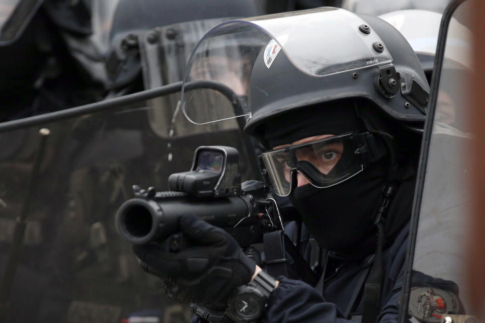 A police officer aims a flash ball gun during clashes with yellow vest protesters on the famed Champs Elysees avenue in Paris, France, Saturday, Jan. 12, 2019. Authorities deployed 80,000 security forces nationwide for a ninth straight weekend of anti-government protests. (AP Photo/Thibault Camus)