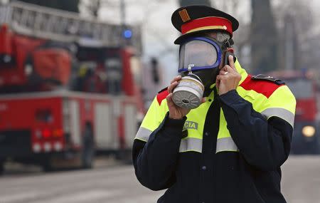 A Catalan "Mosso d'Esquadra" police officer wearing a gas mask speaks on a mobile phone after an explosion at a chemical plant caused a toxic cloud to spread over Igualada near Barcelona February 12, 2015. REUTERS/Stringer