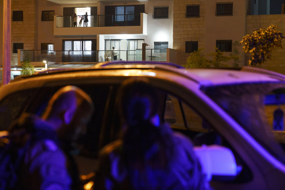 Jewish residents look out from an apartment as police stop a car in the Arab-Jewish town of Lod, central Israel, Friday, May 28, 2021, a week after a cease-fire went into effect in the 11-day war between Gaza's Hamas rulers and Israel. Lod and other mixed cities recently experienced ethnic clashes as groups of Arabs and Jews fought each other in the streets and torched cars, businesses and homes. (AP Photo/David Goldman)