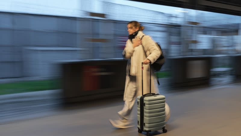 A person with their suitcase enters a terminal at LaGuardia Airport in New York, Tuesday, Nov. 21, 2023. Read on to learn more about packing efficiently for your travels. (AP Photo/Peter K. Afriyie)