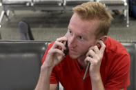 German tourist Steffen Schmieg speaks on a phone inside the Christchurch Airport terminal as he waits to check in for a charter flight back to Germany via Vancouver from Christchurch, New Zealand, Monday, April 6, 2020. Schmieg is among an estimated 100,000 tourists who found themselves stranded in New Zealand after it went into a strict lockdown 12 days ago in an attempt to limit the spread of the coronavirus. Schmieg, 26, said he traveled to New Zealand a month ago to visit a friend and tour the country. He managed to see his friend in time but has been holed up at an Airbnb since the lockdown began. (AP Photo/Mark Baker)