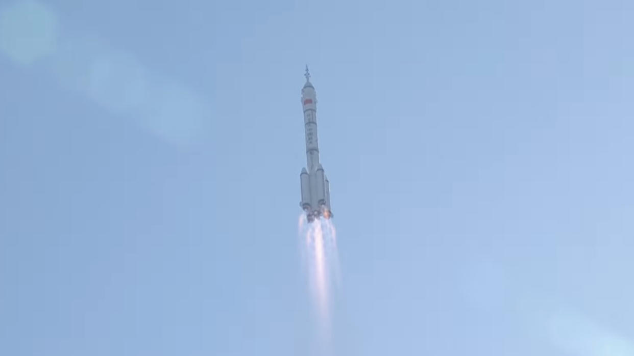  A white rocket launches into a blue sky. 