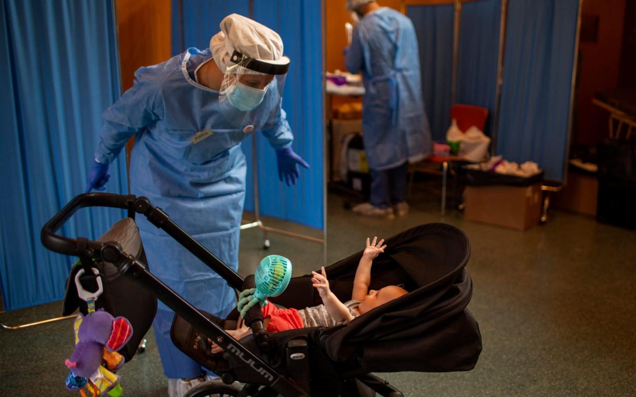 Volunteer of the Spanish NGO Open Arms Julia Martin, 38, plays with 4-month old Biel, as his father takes a test