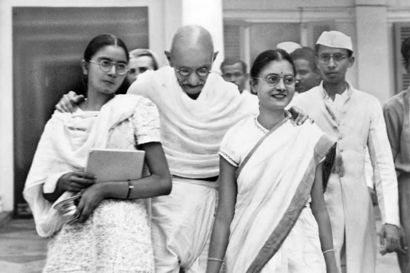 Mahatma Gandhi stands with his arms around two female relatives in New Delhi, India, ca. 1947. On May 5, 1930, British and Indian troops were put on alert in the major cities throughout India following the arrest and incarceration of Gandhi. File Photo by Bert Brandt/Acme Newspictures/UPI