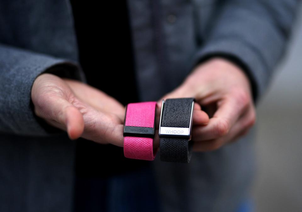 A woman holds a pair of Whoop wearable devices in her hands.