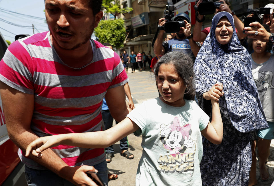 A man helps a wounded girl and a woman to an ambulance after an Israeli airstrikes at their building, in Gaza City, Tuesday, May 11, 2021. (AP Photo/Adel Hana)