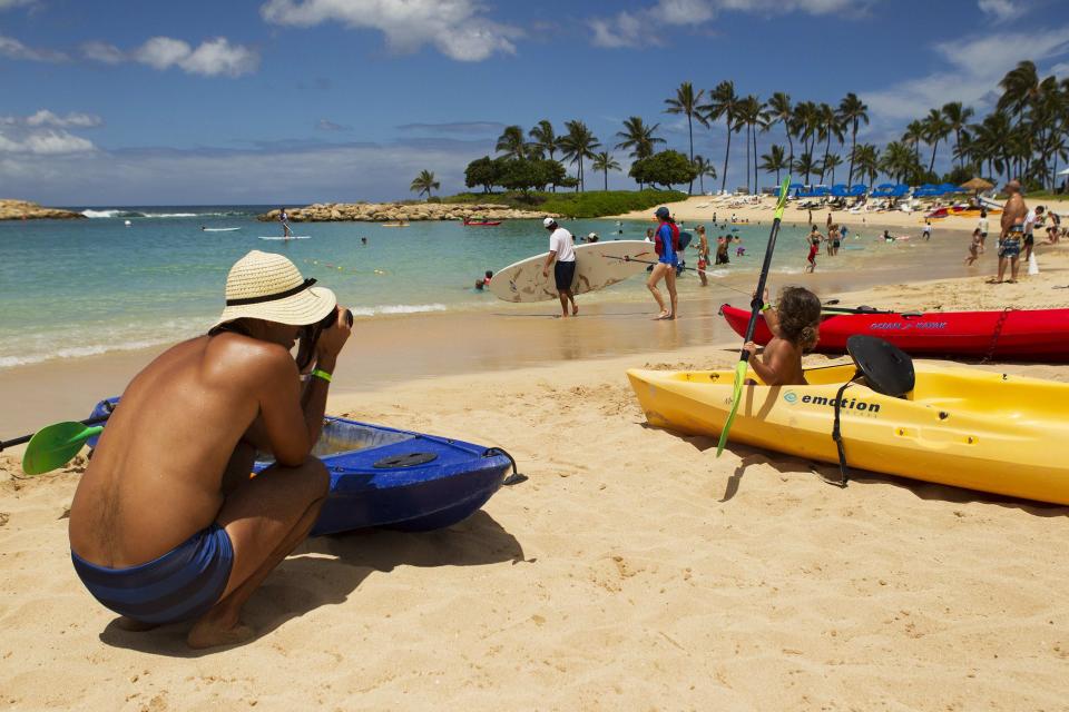 Mike Wilson takes a picture of his son playing in a kayak on the beach as two hurricanes approach the Hawaiian islands, in Honolulu, Hawaii, August 6, 2014. Hawaiians braced for a one-two punch from a pair of major storms headed their way on Wednesday, as Hurricane Iselle bore down on the islands packing high winds and heavy surf and Julio, tracking right behind, was upgraded to hurricane status. REUTERS/Hugh Gentry (UNITED STATES - Tags: ENVIRONMENT DISASTER SOCIETY)