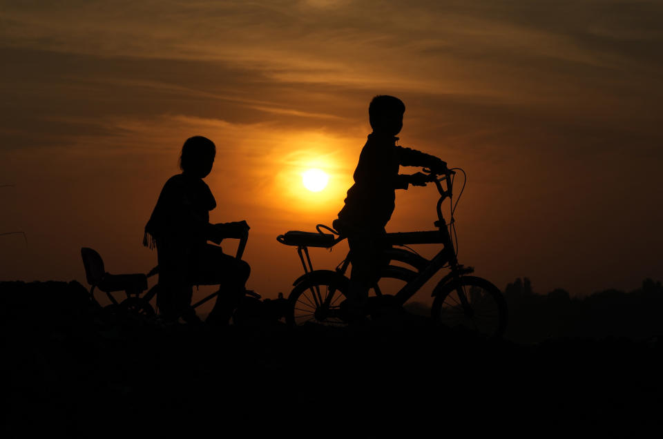 Children ride bycile during the last sunset of 2022 in Lahore, Pakistan, Saturday, Dec. 31, 2022. (AP Photo/K.M. Chaudary)