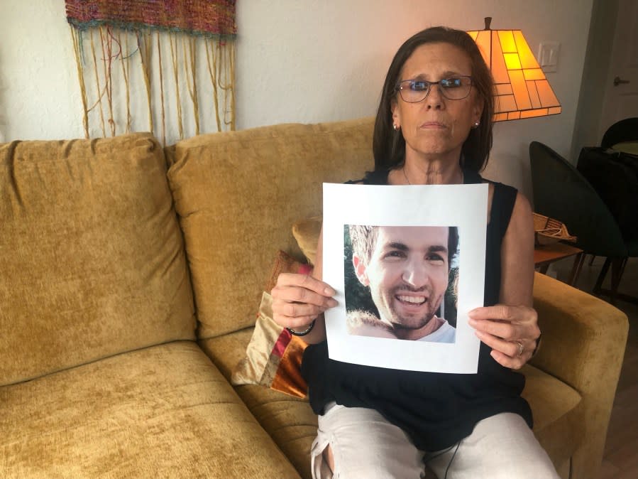 Gillian Kaye holding a photo of her stepson Sagui Dekel-Chen (WFLA)