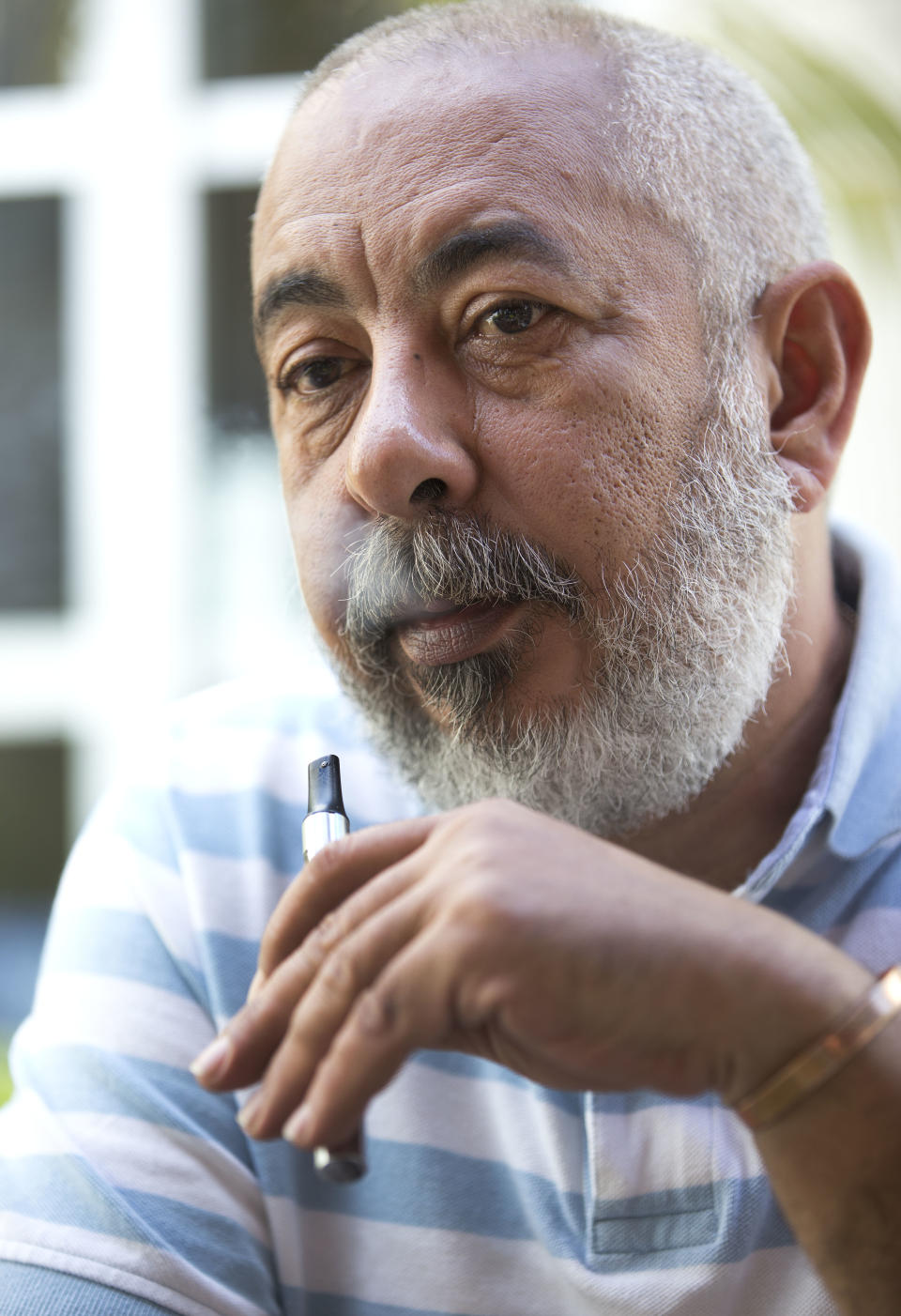 Cuban author Leonardo Padura smokes an electronic cigarette after having smoked a real one during an interview in Coral Gables, Fla., Wednesday, Feb. 19, 2014. photo, Padura is the most internationally well-known living author on the island - one who has managed to carve a space in which he can cast a critical eye while being neither a member of the community party, nor a dissident. (AP Photo/Wilfredo Lee)