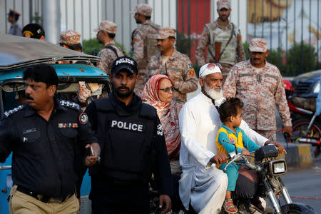 A man with his family rides past police officers and paramilitary soldiers guarding a road during a protest, after the Supreme Court overturned the conviction of a Christian woman sentenced to death for blasphemy against Islam, in Karachi, Pakistan November 2, 2018. REUTERS/Akhtar Soomro/File Photo