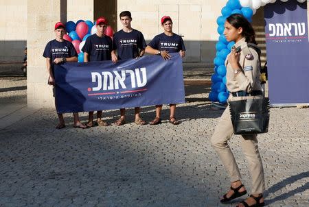 An Israeli soldier walks past members of the U.S. Republican party's election campaign team in Israel, who are holding a banner in support of Republican U.S. presidential nominee Donald Trump, during a campaign aimed at potential American voters living in Israel, near a mall in Modi'in, Israel August 15, 2016. REUTERS/Baz Ratner