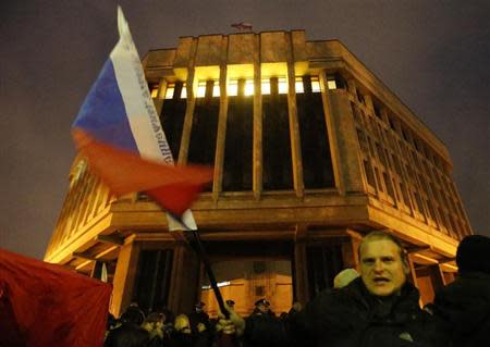 A man waves a Russian flag in front of a local parliament building during a pro-Russian rally in Simferopol, Crimea February 27, 2014. REUTERS/David Mdzinarishvili