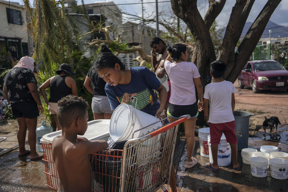 Siblings collect water from a public well in the aftermath of Hurricane Otis in Acapulco, Mexico, Friday, Oct. 27, 2023. Hundreds of thousands of people's lives were torn apart when the fastest intensifying hurricane on record in the Eastern Pacific shredded the coastal city of 1 million. (AP Photo/Felix Marquez)