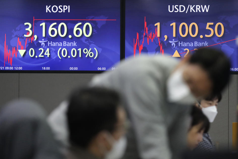 Currency traders talk near the screens showing the Korea Composite Stock Price Index (KOSPI), left, and the foreign exchange rate between U.S. dollar and South Korean won at the foreign exchange dealing room in Seoul, South Korea, Friday, Jan. 22, 2021. Asian stock markets retreated Friday after a resurgence of coronavirus infections in China and a rise in cases in Southeast Asia.(AP Photo/Lee Jin-man)
