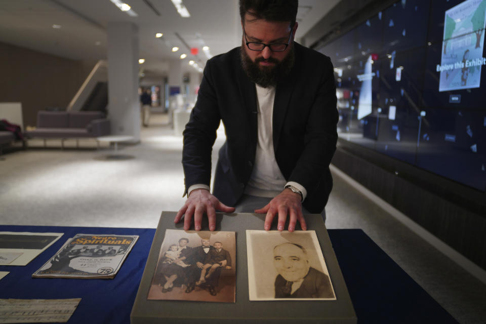 Christopher Lynch, music historian and project coordinator with the Center for American Music at the University of Pittsburgh, adjusts a set of photos of gospel musician, composer and publisher Charles Henry Pace and his family, on Tuesday, Feb. 28, 2023, at the University of Pittsburgh, in Pittsburgh. When organizing the Pace archives, which are housed and owned by the university, Lynch discovered the composer was an early pioneer of gospel music and one of the early and only publishers of Black artists in the niche genre. (AP Photo/Jessie Wardarski)