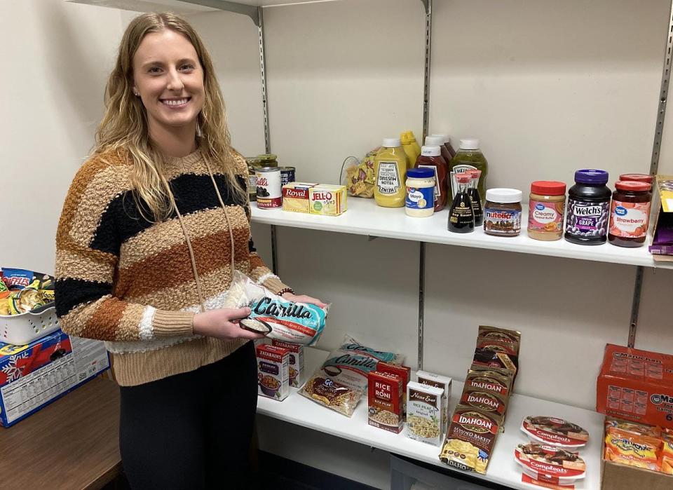 Corrin Toscano, a 22-year-old Gannon University graduate student, holds a bag of rice inside the Erie school's food pantry, Store U-Knighted. Toscano helps tend to the Store U-Knighted as part of her work-study job.