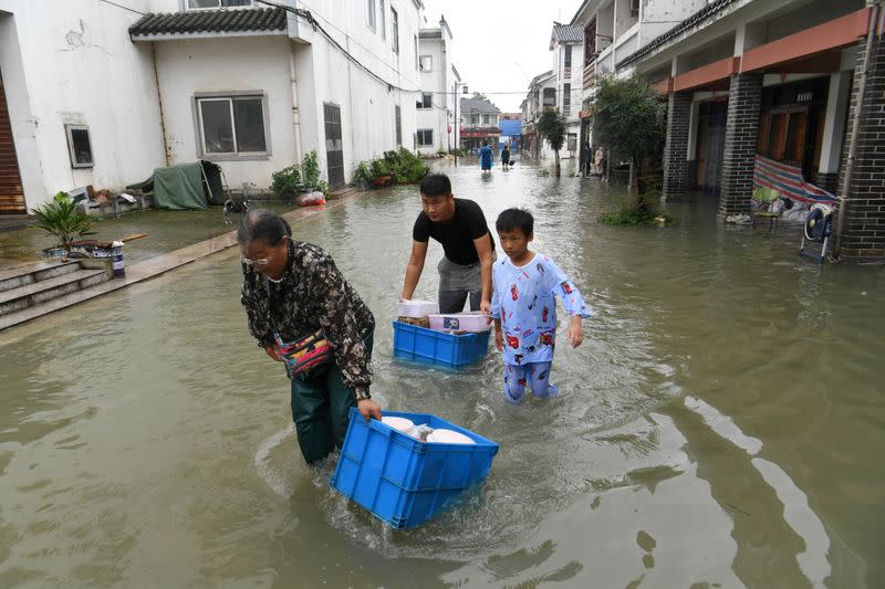 People wade through floodwaters as they move their belongings at a flooded tourist attraction near the Chao Lake in Hefei