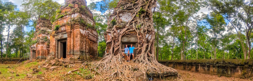 Brent and Michael standing in front of ruins covered with vines. 