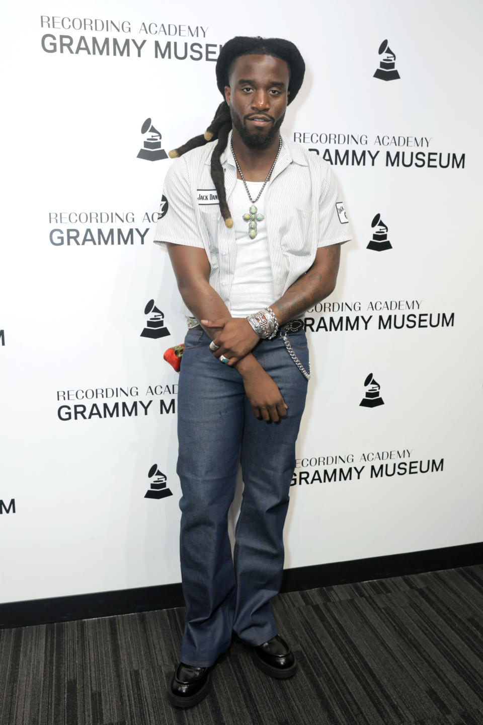 A man dressed in a short-sleeved shirt and jeans poses at the Grammy Museum event