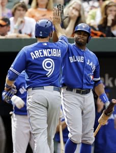 Toronto Blue Jays' J.P. Arencibia, left, high-fives Rajai Davis after scoring a run on a bases-loaded walk in the 11th inning of a baseball game against the Baltimore Orioles, Wednesday, April 24, 2013, in Baltimore. Toronto won 6-5. (AP Photo/Patrick Semansky)