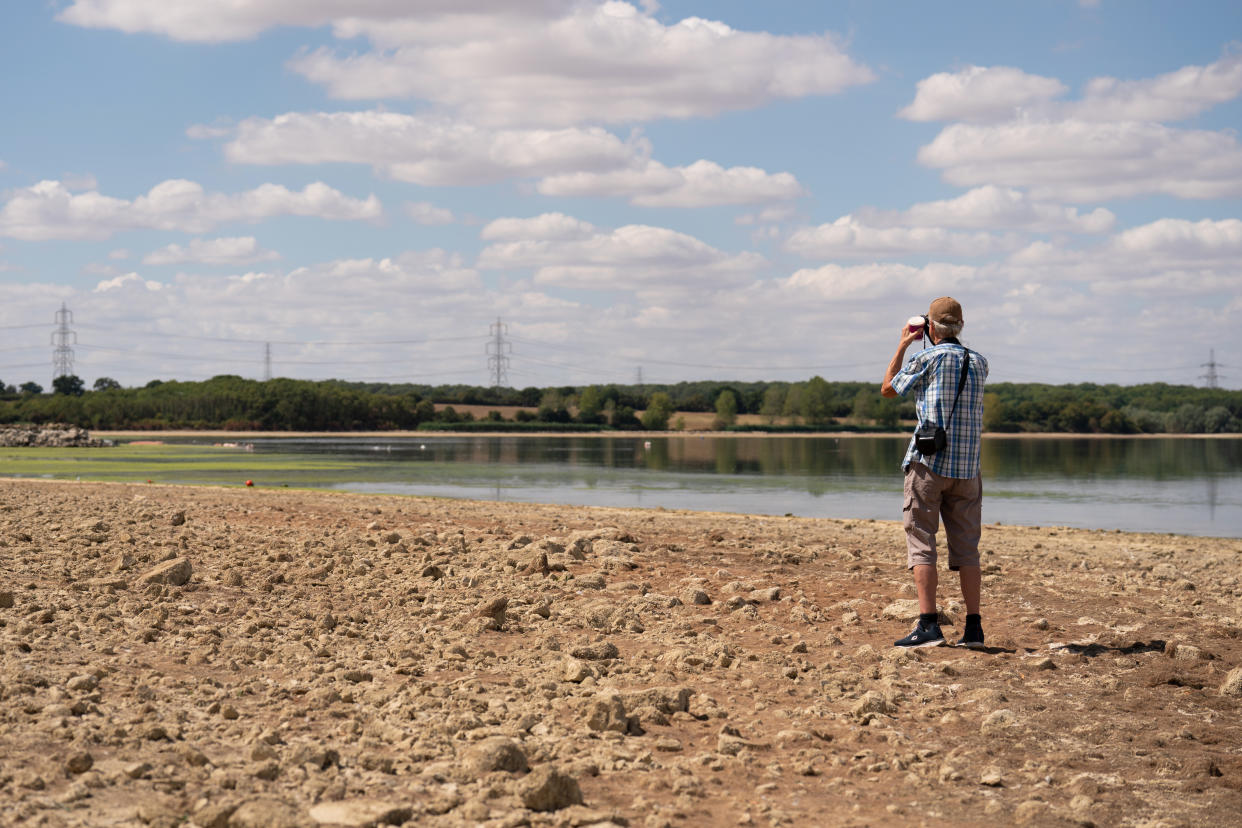 A man stands in the basin of Grafham Water near Huntingdon in Cambridgeshire, where water is receding during the drought. Britain is braced for another heatwave that will last longer than July's record-breaking hot spell, with highs of up to 35C expected next week. Picture date: Monday August 8, 2022.