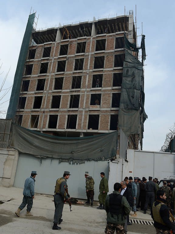 Afghan security offficials stand beside the body of a would-be suicide bomber in Kabul on February 24, 2013. An AFP photographer at the scene saw a young man laying dead in a pool of blood next to his bullet-ridden car on the side of the road near a construction site