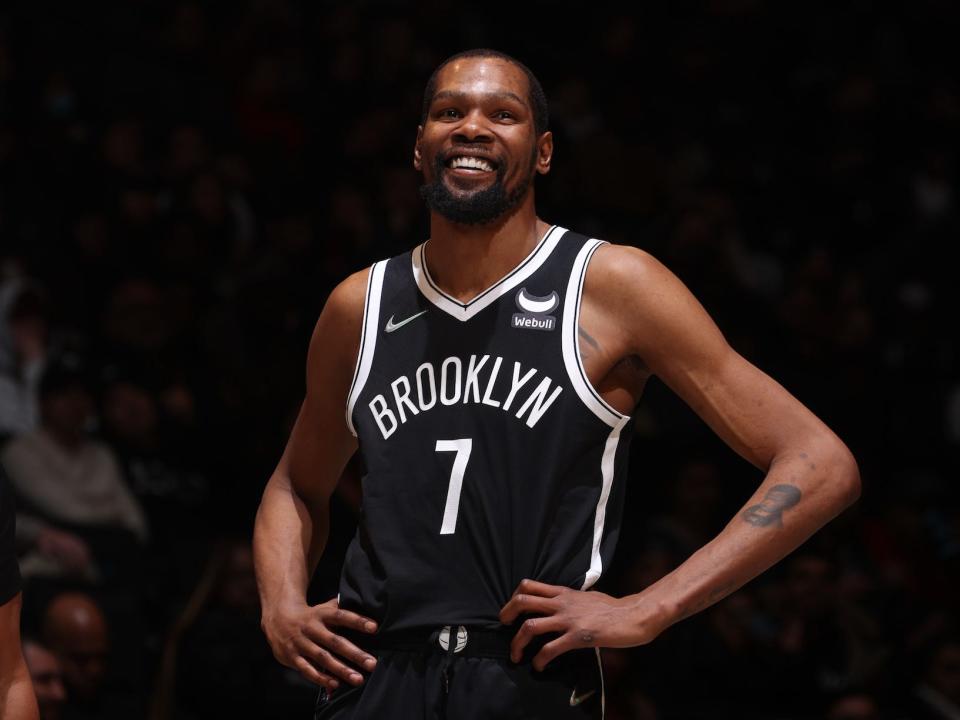 Kevin Durant stands with his hands on his hips and smiles during a Nets game in 2022.