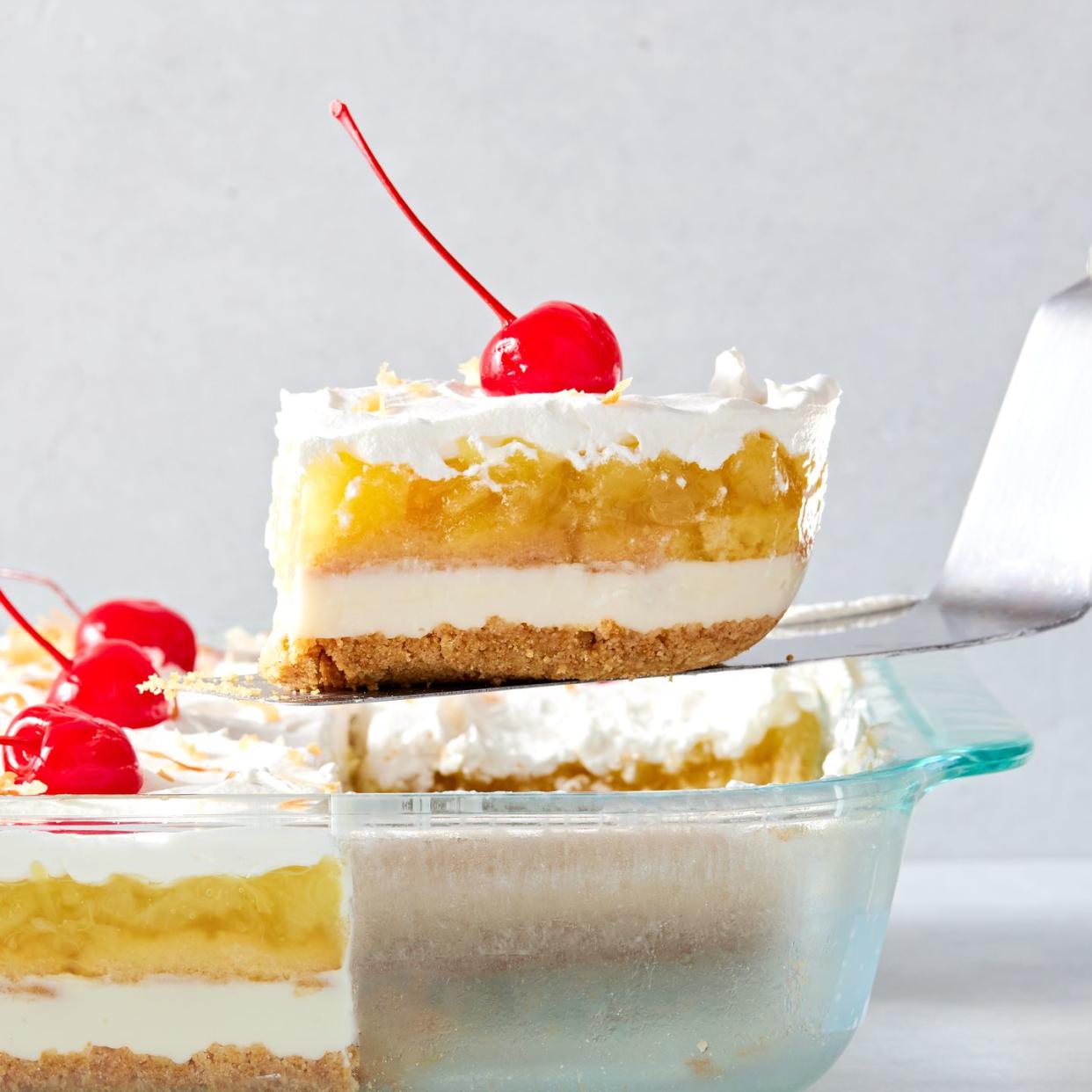 creamy coconut lime cheesecake layered with buttery shortbread cookies, crushed pineapple jello, cool whipped cream, and maraschino cherries all on a graham cracker coconut crust