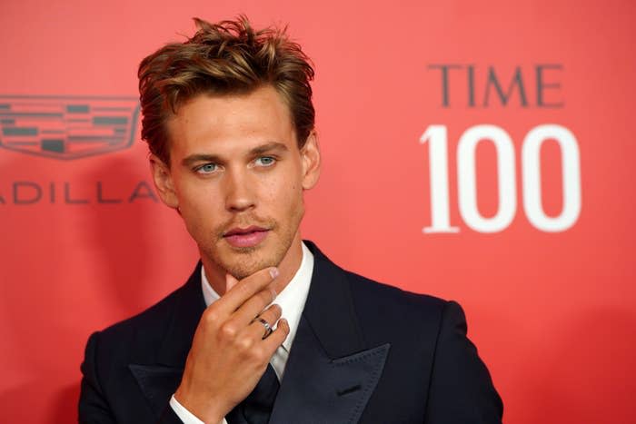 Closeup of Austin Butler with his hand on his chin as he walks the red carpet