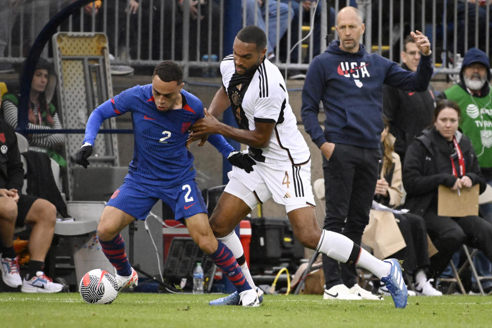 United States' Sergino Dest, left, is pressured by Germany's Jonathan Tah as United States head coach Gregg Berhalter, right, looks on, during an international friendly soccer match at Pratt & Whitney Stadium at Rentschler Field, Saturday, Oct. 14, 2023, in East Hartford, Conn. (AP Photo/Jessica Hill)