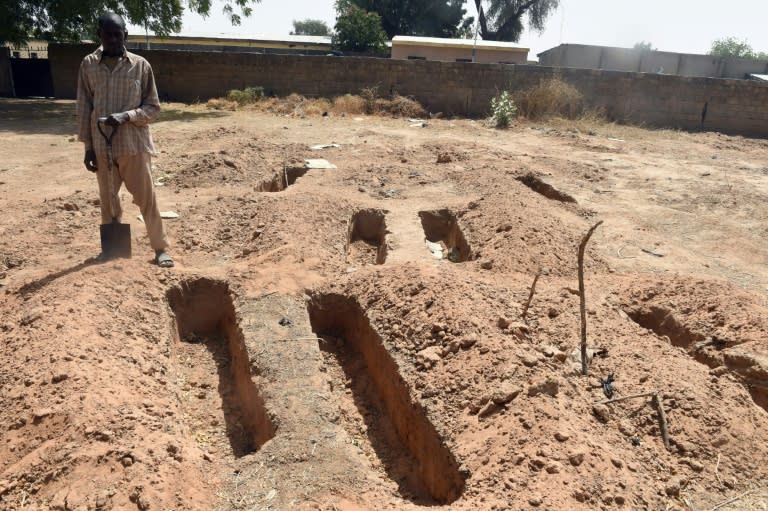 A grave-digger stands beside gaves dug for victims or dead members of Boko Haram Islamists expected for burial at Gwange Cemetery in Maiduguri, northeast Nigeria, on February 2, 2016