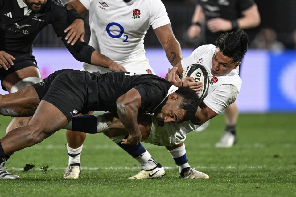 England's Marcus Smith, right, is tackled by New Zealand's Sevu Reece during their rugby union test match in Dunedin, New Zealand, Saturday July 6, 2024. (Andrew Cornaga/Photosport via AP)