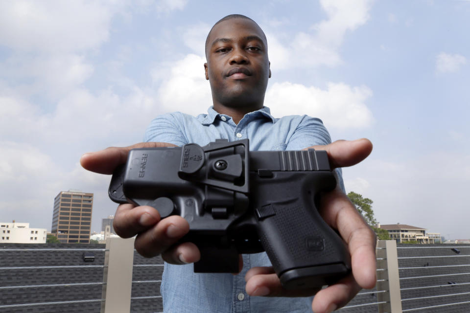 Charles Blain, a new gun owner, poses with his holstered 9mm Glock 43 handgun, Monday, May 3, 2021, on the parking garage of his apartment complex in Houston. Blain also owns a shotgun and is currently completing his concealed carry license requirements to carry the handgun. Blain, who describes himself as a conservative, says "pandemic-related unemployment crime" and repeated calls over the past year to release hundreds of jail inmates because of soaring COVID-19 infections pushed him to buy. (AP Photo/Michael Wyke)