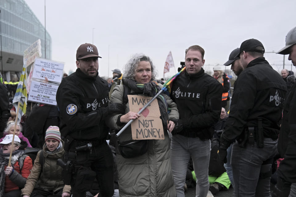 Police detain climate activists blocking the main highway around Amsterdam near the former headquarters of a ING bank to protest its financing of fossil fuels, Saturday, Dec. 30, 2023. Protestors walked onto the road at midday, snarling traffic around the Dutch capital in the latest road blockade organized by the Dutch branch of Extinction Rebellion. (AP Photo/Patrick Post)