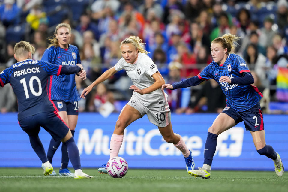 Angel City FC forward Claire Emslie, center, moves the ball against OL Reign midfielder Jess Fishlock, left, and defender Emily Sonnett (2) during the first half of an NWSL quarterfinal playoff soccer match Friday, Oct. 20, 2023, in Seattle. (AP Photo/Lindsey Wasson)