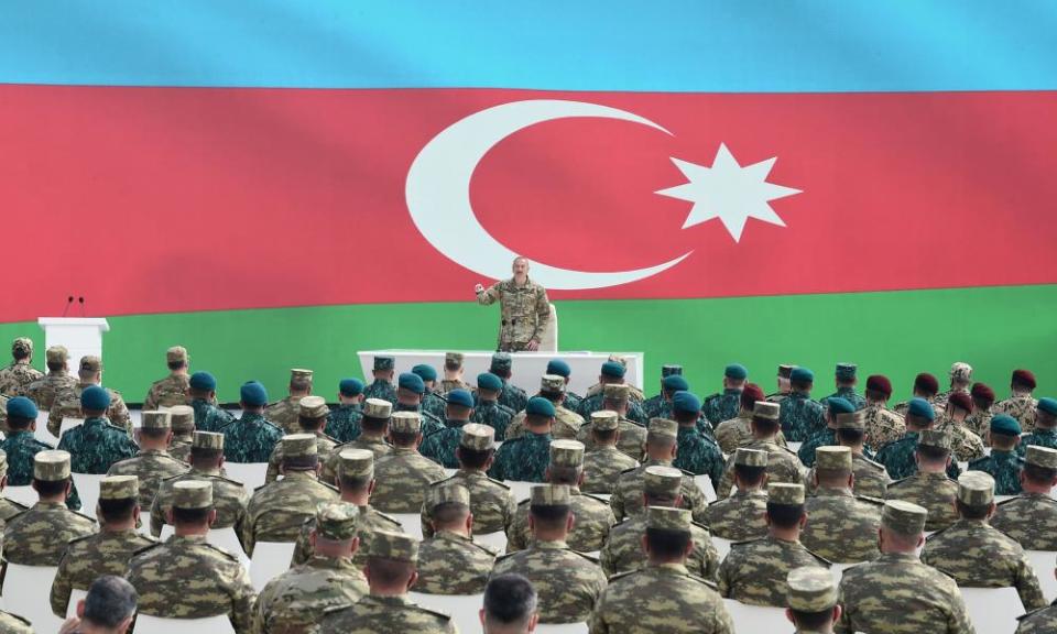 aliyev speaks with soldiers in front of flag