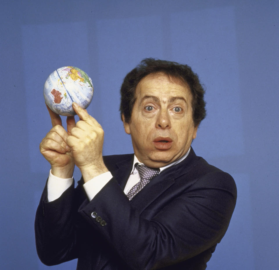 Comedian Jackie Mason holding small globe w tips of his fin (Mario Ruiz / Getty Images)