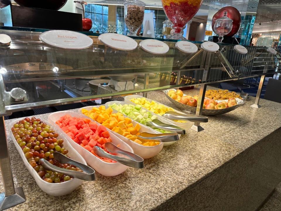 Large containers of grapes and sliced melons with tongs in each at the Bacchanal buffet