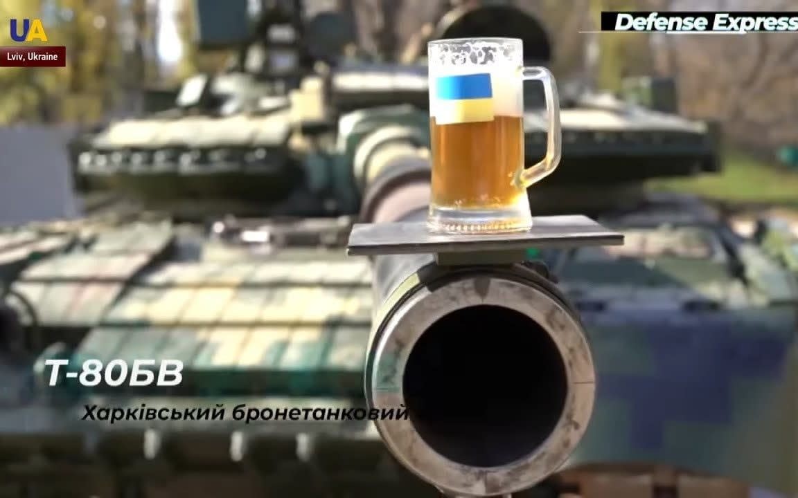 Beer is balanced on the end of the gun on a Leopard tank to demonstrate its steadiness