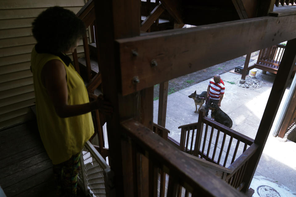 Jacqueline Anderson watches as her husband, Michael Williams, takes their dogs, Lily and Shibey, out in the backyard of their home Tuesday, July 27, 2021, on the South Side of Chicago. For days after Safarian Herring's fatal shooting, Williams’ wife said he curled up on his bed, having flashbacks and praying for his passenger. (AP Photo/Charles Rex Arbogast)