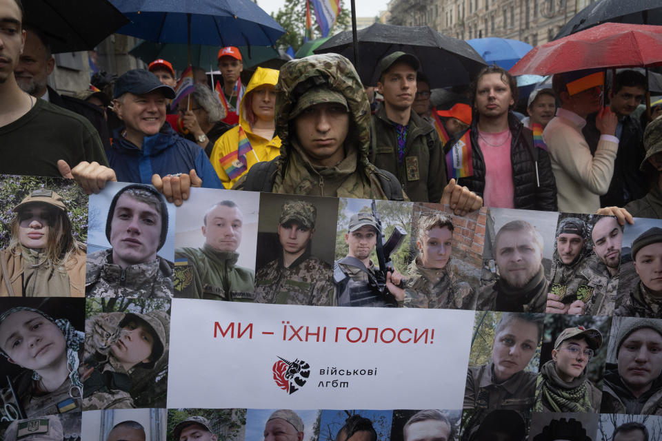 Activist soldiers hold portraits of LGBT Ukrainian servicemen, who are fighting on the frontline, with the poster reading "We are their voices" in Kyiv, Ukraine, Sunday, June 16, 2024. Several hundred LGBT Ukrainian servicemen and other protesters joined a pride march in central Kyiv Sunday seeking legal reforms to allow people in same-sex partnerships to take medical decisions for wounded soldiers and bury victims of the war with Russia that extended across Ukraine more than two years ago. (AP Photo/Efrem Lukatsky)