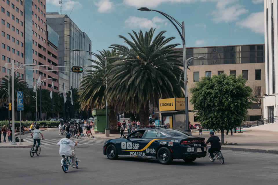 Members of Los Chilangos pass a police car in Mexico City in 2017.